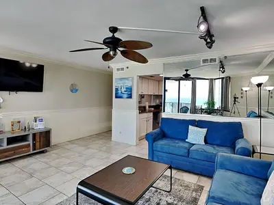a living room with a blue couch and a table at Sunbird Beach Resort #902 West in Panama City Beach