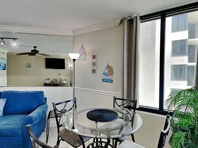a living room with a blue couch and a glass table at Sunbird Beach Resort #902 West in Panama City Beach