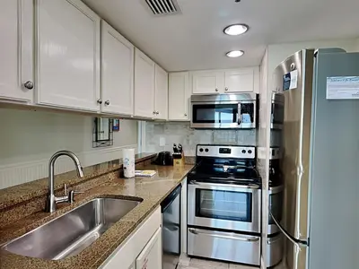 a kitchen with white cabinets and stainless steel appliances at Sunbird Beach Resort #902 West in Panama City Beach