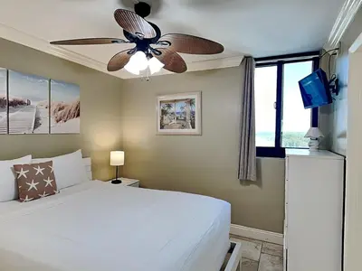 a bedroom with a white bed and a ceiling fan at Sunbird Beach Resort #902 West in Panama City Beach