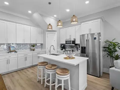 a kitchen with white cabinets and a kitchen island with stools at Deja Blue in Panama City Beach