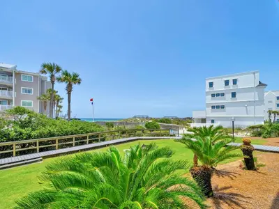 a park with palm trees in front of a building at Beachside Villas 613 in Santa Rosa Beach