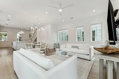 a living room with white furniture and a kitchen at 69 E Trigger Trail by 30A Escapes in Rosemary Beach