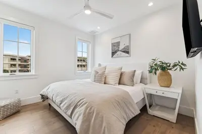 a white bedroom with a bed and windows at 69 E Trigger Trail by 30A Escapes in Rosemary Beach