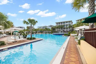 a swimming pool at a resort with palm trees at 69 E Trigger Trail by 30A Escapes in Rosemary Beach