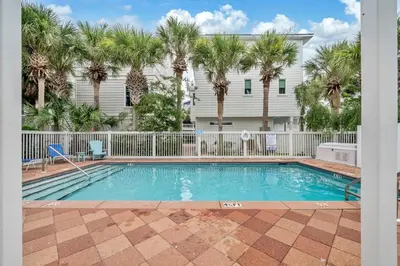 a swimming pool in front of a house with palm trees at Grouper Therapy in Santa Rosa Beach