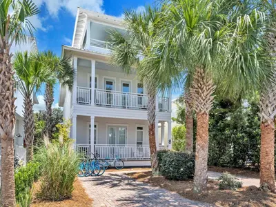 a white house with palm trees in front of it at Calliope in Rosemary Beach