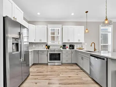 a kitchen with white cabinets and stainless steel appliances at Calliope in Rosemary Beach