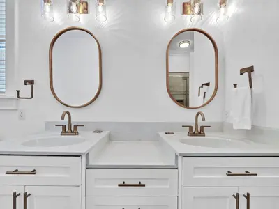two sinks in a bathroom with two mirrors at Calliope in Rosemary Beach
