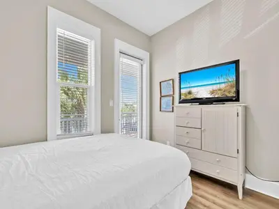 a bedroom with a bed and a flat screen tv at Calliope in Rosemary Beach