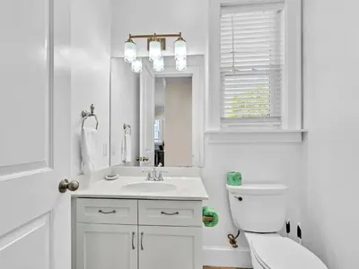 a white bathroom with a toilet and a sink at Calliope in Rosemary Beach