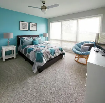 a bedroom with blue walls and a bed and a chair at Blue By The Bay in Panama City Beach