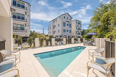a swimming pool with chairs and a building at Casa DAzure by Travel Life Vacations in Santa Rosa Beach