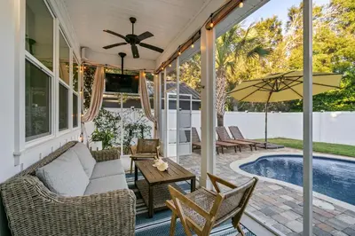 a screened porch with a couch and chairs and a pool at Gone Coastal by Travel Life Vacations in Seacrest
