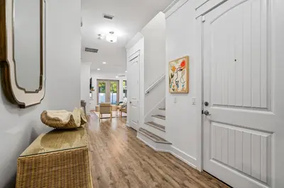 a hallway with white walls and a door and a bench at Gone Coastal by Travel Life Vacations in Seacrest