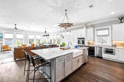 an open kitchen with white cabinets and a large island at Grand Pearl by Travel Life Vacations in Rosemary Beach