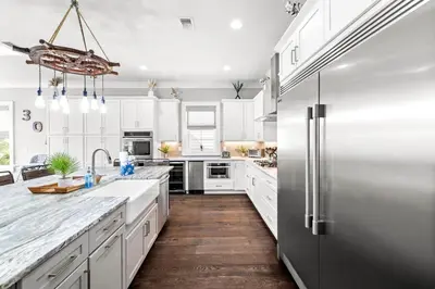 a kitchen with white cabinets and a stainless steel refrigerator at Grand Pearl by Travel Life Vacations in Rosemary Beach