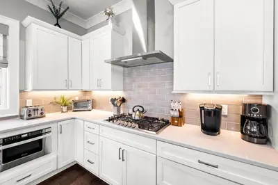 a white kitchen with white cabinets and a stove top oven at Grand Pearl by Travel Life Vacations in Rosemary Beach