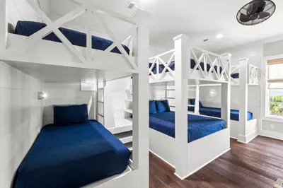 two bunk beds in a white room with blue sheets at Grand Pearl by Travel Life Vacations in Rosemary Beach