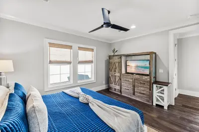 a bedroom with a blue bed and a flat screen tv at Grand Pearl by Travel Life Vacations in Rosemary Beach