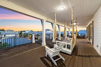 a porch with two chairs and a swing at Grand Pearl by Travel Life Vacations in Rosemary Beach