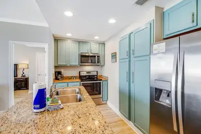 a kitchen with blue cabinets and stainless steel appliances at Ocean Front Condo Panama City Beach in Panama City Beach