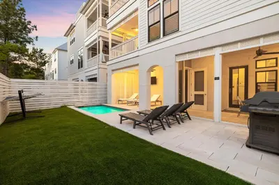 a backyard with a pool and chairs and a grill at Long To Sea by Travel Life Vacations in Santa Rosa Beach