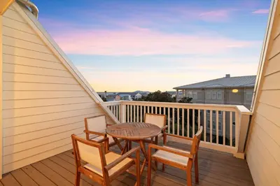 a patio with a table and chairs on a balcony at Long To Sea by Travel Life Vacations in Santa Rosa Beach