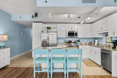 a kitchen with white cabinets and blue chairs at Laketown Wharf #1305 in Panama City Beach