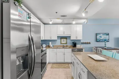 a kitchen with white cabinets and a stainless steel refrigerator at Laketown Wharf #1305 in Panama City Beach