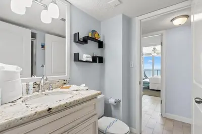 a bathroom with a sink and a toilet and a mirror at Dunes of Panama C605 in Panama City Beach