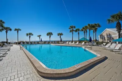 a swimming pool with chairs and palm trees at Dunes of Panama C605 in Panama City Beach