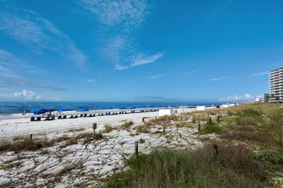 a beach with chairs and umbrellas and the ocean at Hidden Dunes 1605 in Panama City Beach