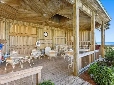 a wooden deck with tables and chairs and a clock at Hidden Dunes 1605 in Panama City Beach