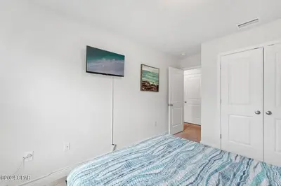 a white bedroom with a bed and two pictures on the wall at Panama City Beach Cozy Townhouse in Panama City Beach