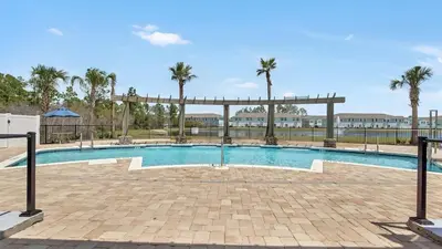 a swimming pool with palm trees in the background at Panama City Beach Cozy Townhouse in Panama City Beach