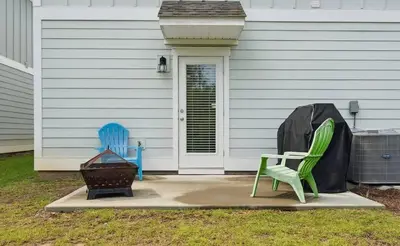two green chairs and a grill in front of a house at Panama City Beach Cozy Townhouse in Panama City Beach