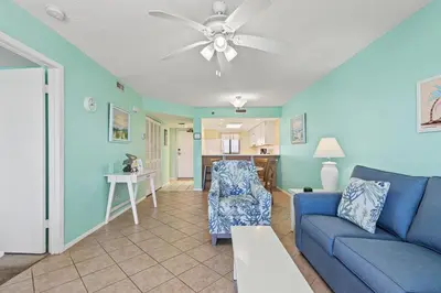 a living room with a blue couch and a table at Commodore 1009 in Panama City Beach