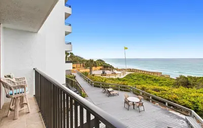 a balcony with tables and chairs and the ocean at One Seagrove Place 0204 in Santa Rosa Beach
