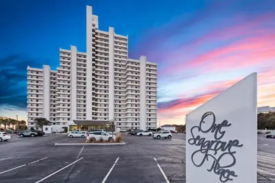 a large building in a parking lot with a sunset at One Seagrove Place 0502 in Santa Rosa Beach