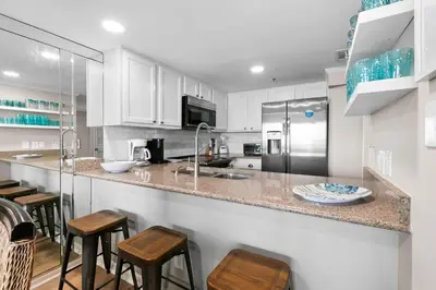 a kitchen with white cabinets and a counter with stools at One Seagrove Place 0904 in Santa Rosa Beach