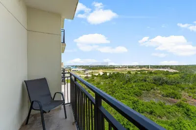 a chair on a balcony with a view of a field at Origin 613 - Studio King - Peaceful Nature View in Panama City Beach