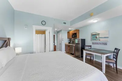 a bedroom with a bed and a desk and a kitchen at Origin 613 - Studio King - Peaceful Nature View in Panama City Beach