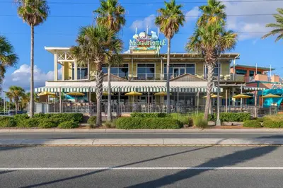 a hotel with palm trees in front of it at Spacious 6BR Beach Home Sleeps 15 – Relax & Reconnect at Coastal Breeze in Panama City Beach