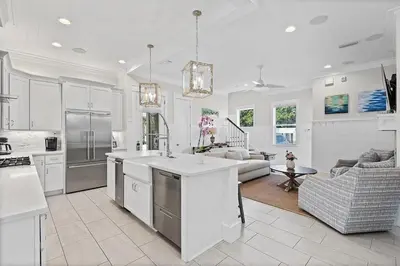 a kitchen with white cabinets and a living room at Mermaid Cove in Inlet Beach