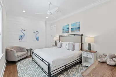 a white bedroom with a bed and a chair at Mermaid Cove in Inlet Beach