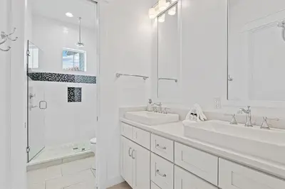 a white bathroom with two sinks and a shower at Mermaid Cove in Inlet Beach