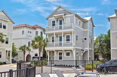 a large white house with a fence and chairs at Mermaid Cove in Inlet Beach