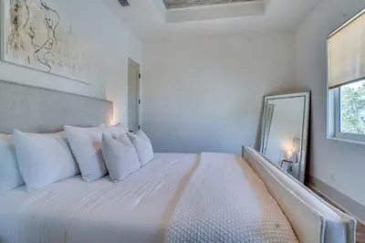 a bedroom with a large white bed with a mirror at No Bad Day on 30A in Inlet Beach