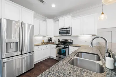 a kitchen with white cabinets and a stainless steel refrigerator at Beach Bliss in Inlet Beach
